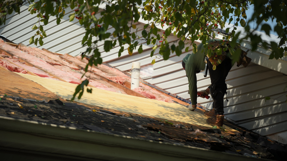 Roofer installing new underlayment and shingles while replacing a Utah home's roof